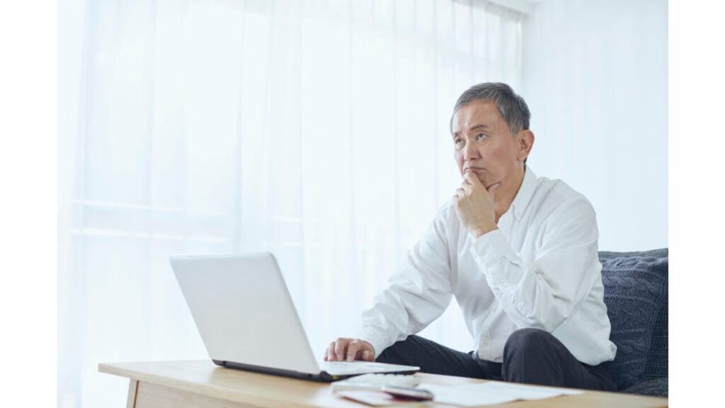パソコンを開いて悩んでいる男性の写真