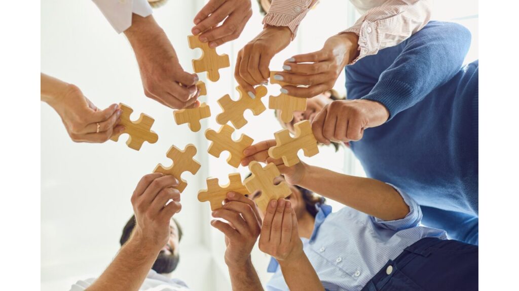 ５、６人がパズルのピースを持ち寄っている写真