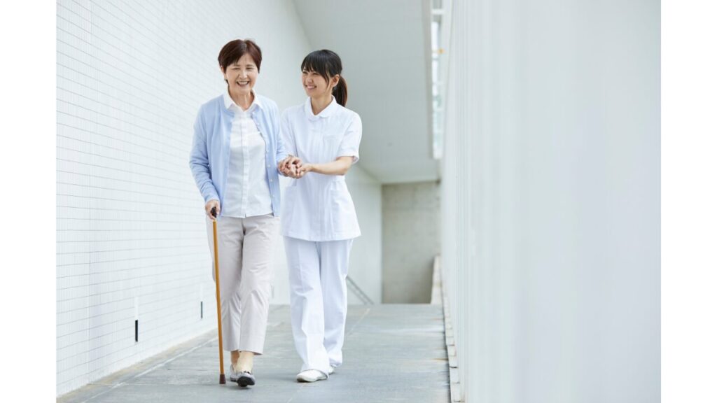 杖歩行の利用者に手を引き引き介助している職員の写真