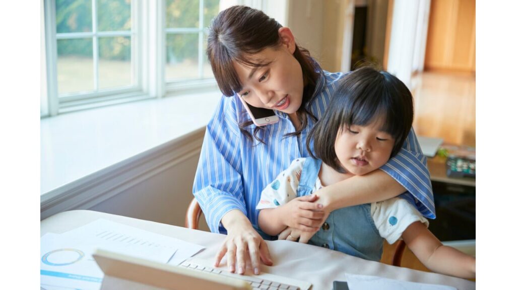 小さい子供を抱えながら仕事をしている女性の写真