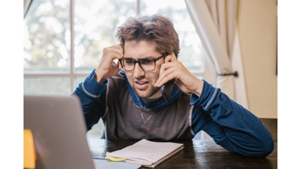 ノートパソコンを見て困惑している男の写真