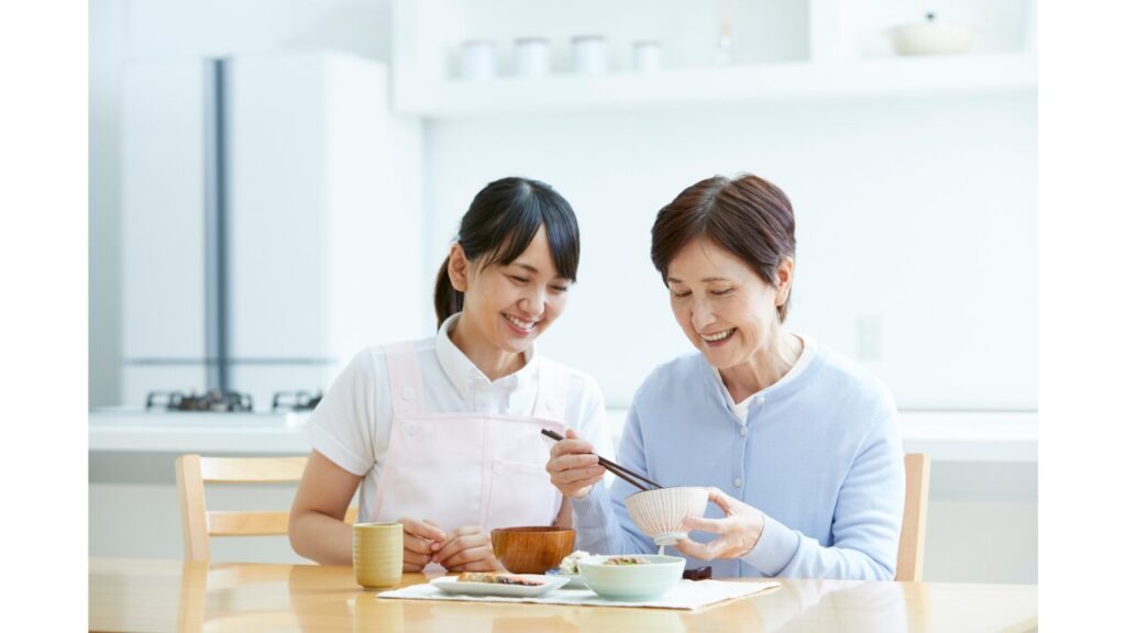 高齢者の食事に介護士が寄り添っている写真