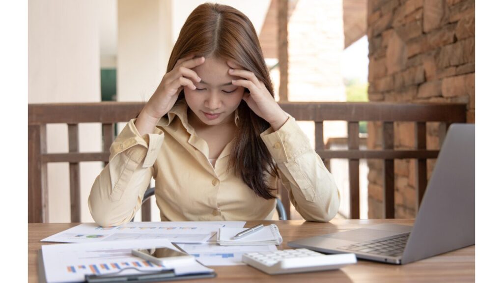 資料を眺め頭を抱える女性の写真